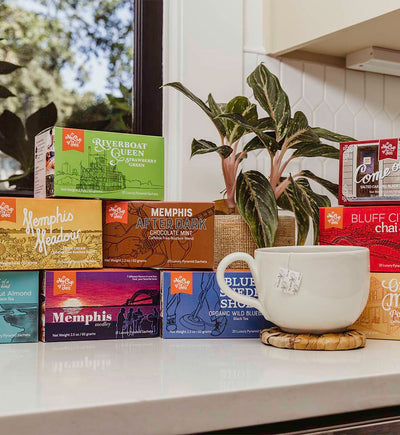 Various tea boxes from My Cup of Tea with a soup mug and banana leaf coaster on white countertop