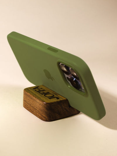 Wood cell phone stand holding phone horizontally on cream backdrop.