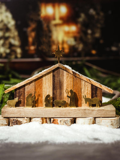 Rustic wooden nativity set with brass silhouette figurines, placed on a snowy base, perfect for holiday decorations, available at Joffa.com as part of the handmade holiday decor collection.