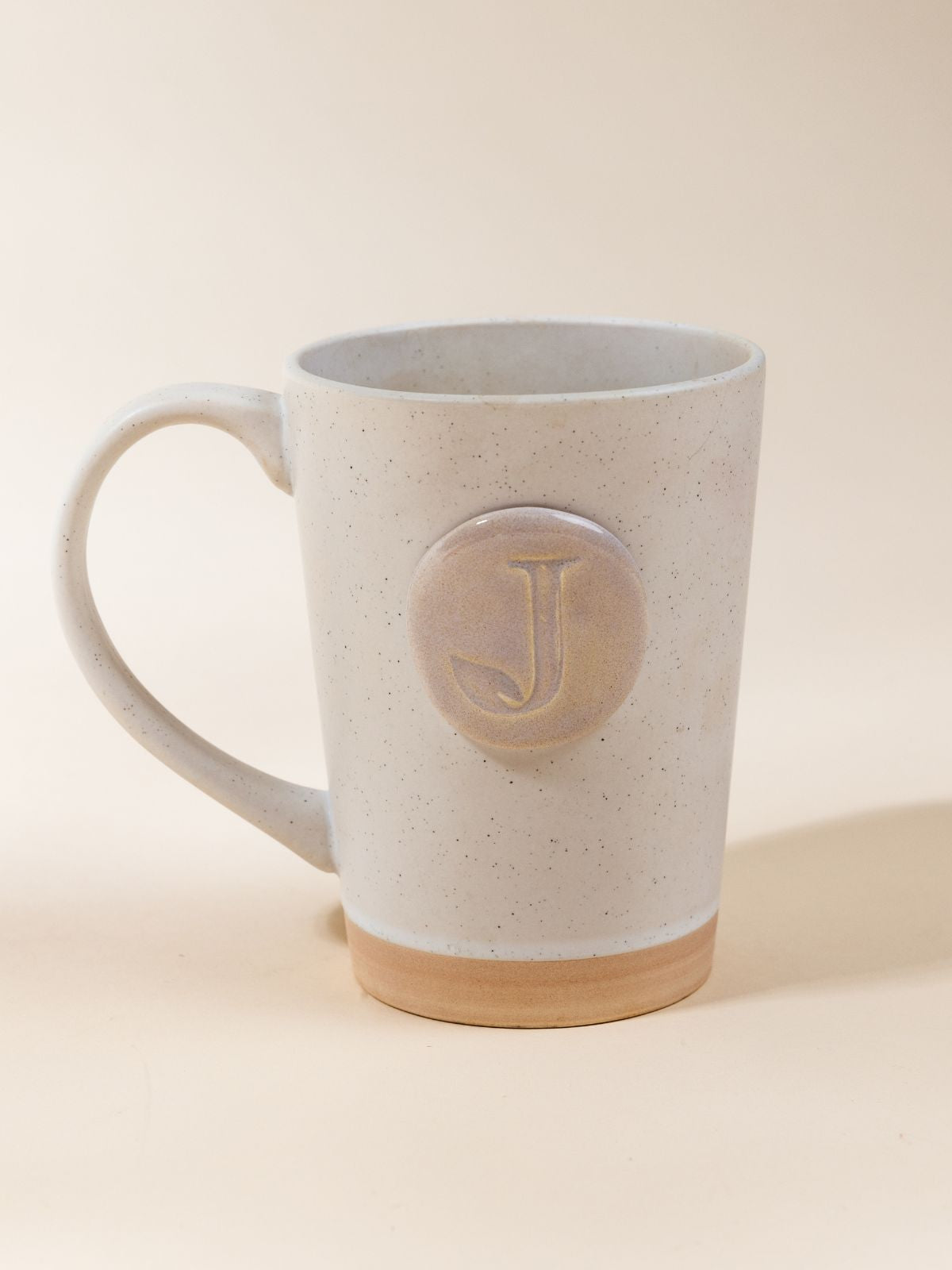 Customizable 16oz white speckled mug on customizable square leather coaster.