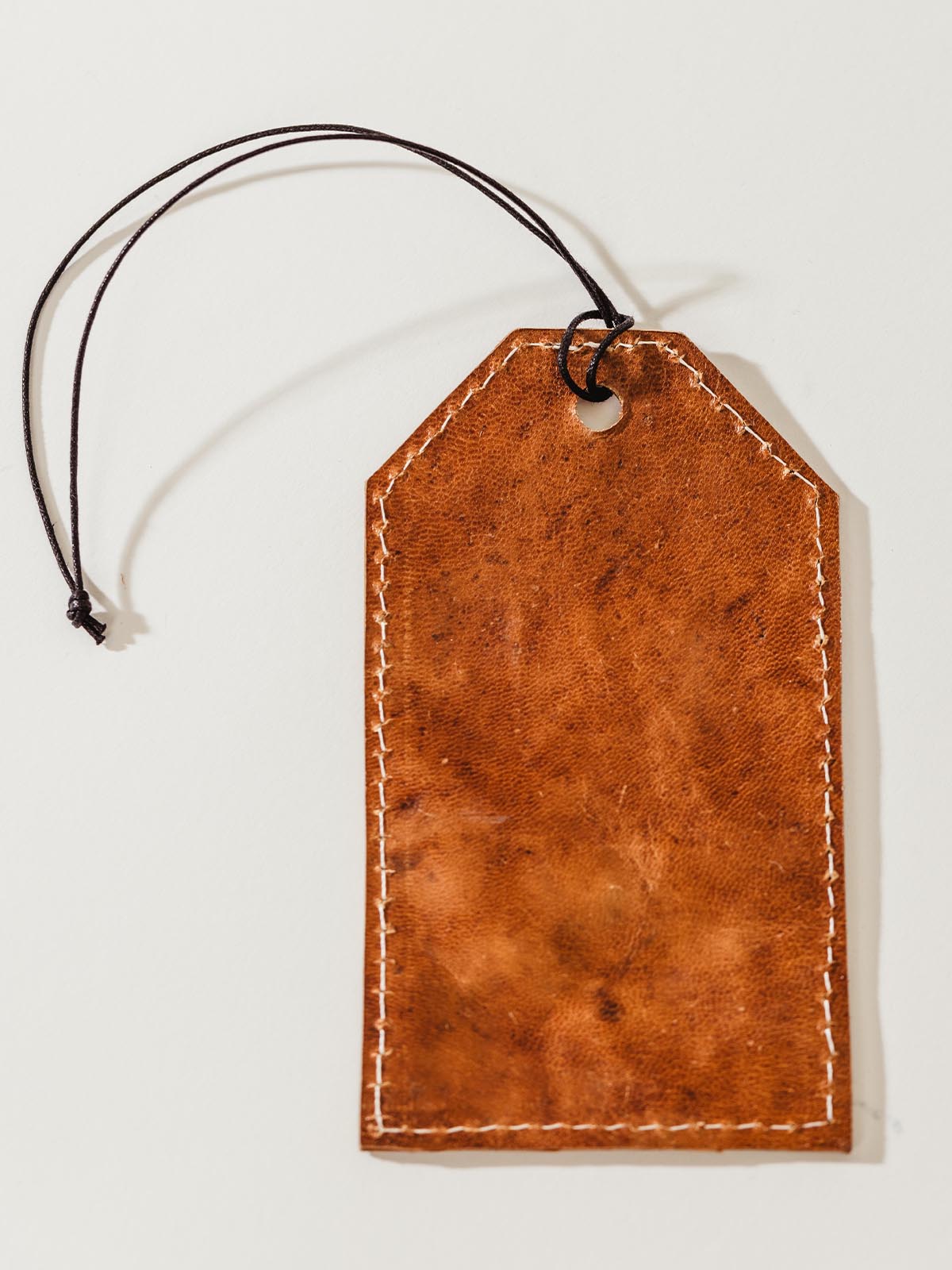 Backside of leather luggage tag on white background.