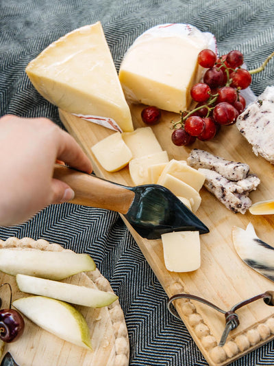 Cheese board with gourmet cheese, fresh grapes, and a handcrafted knife, highlighting Joffa's artisanal kitchenware, perfect for entertaining.