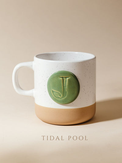 10 oz mug on cream background with tidal pool glazed logo.
