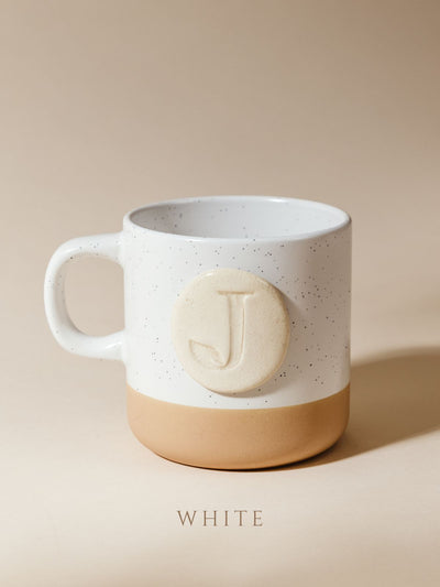 10 oz mug on cream background with white glazed logo.
