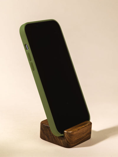 Wood cell phone stand holding phone vertically on cream backdrop.