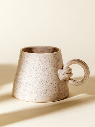 Speckled ceramic mug with an artisan-inspired design, featuring a round handle and neutral tones. Ideal for adding a touch of rustic charm to any kitchen.