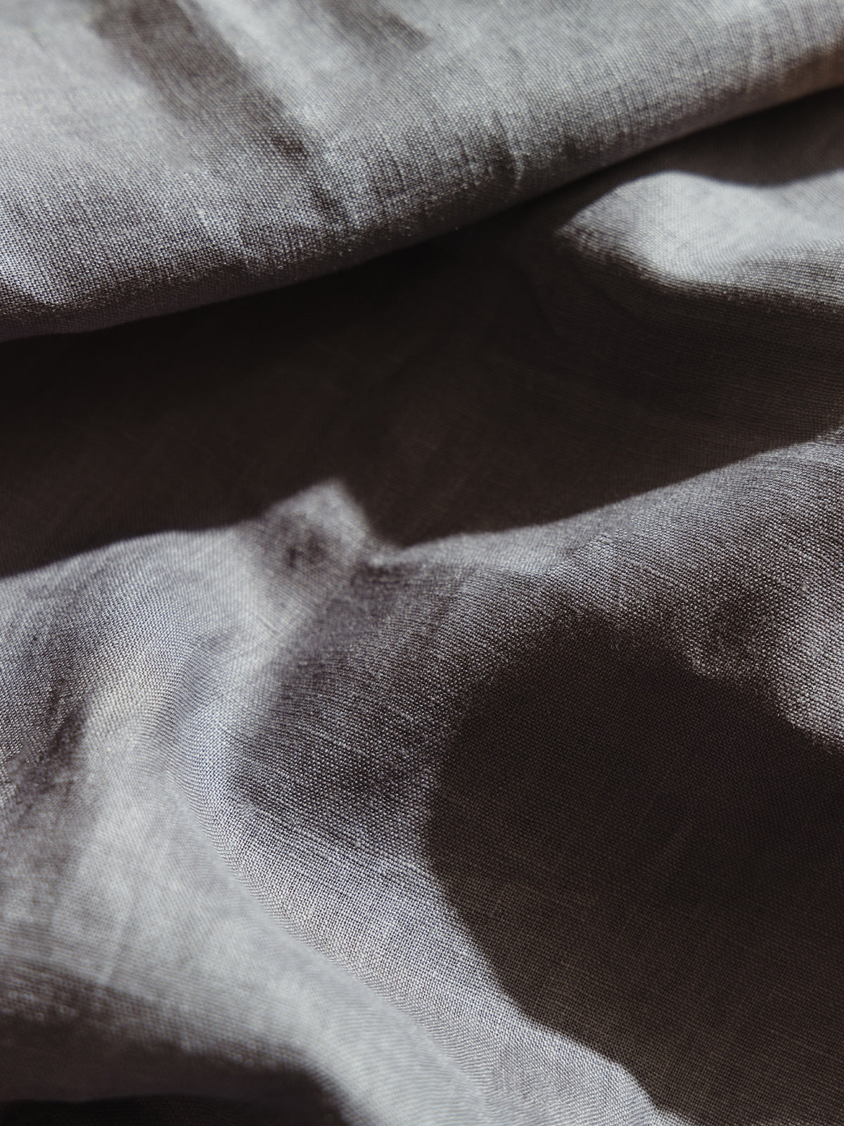 Close-up of a gray linen table runner with soft folds, showcasing its natural texture and lightweight, breathable quality for elegant table settings.