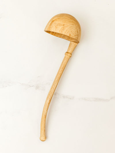 Wooden soup ladle on white granite counter top.