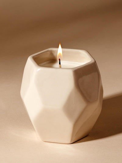 Mini white ceramic prism designed candle on a cream background. 