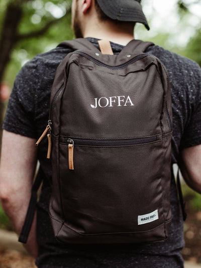 Male model wearing black screen printed backpack.