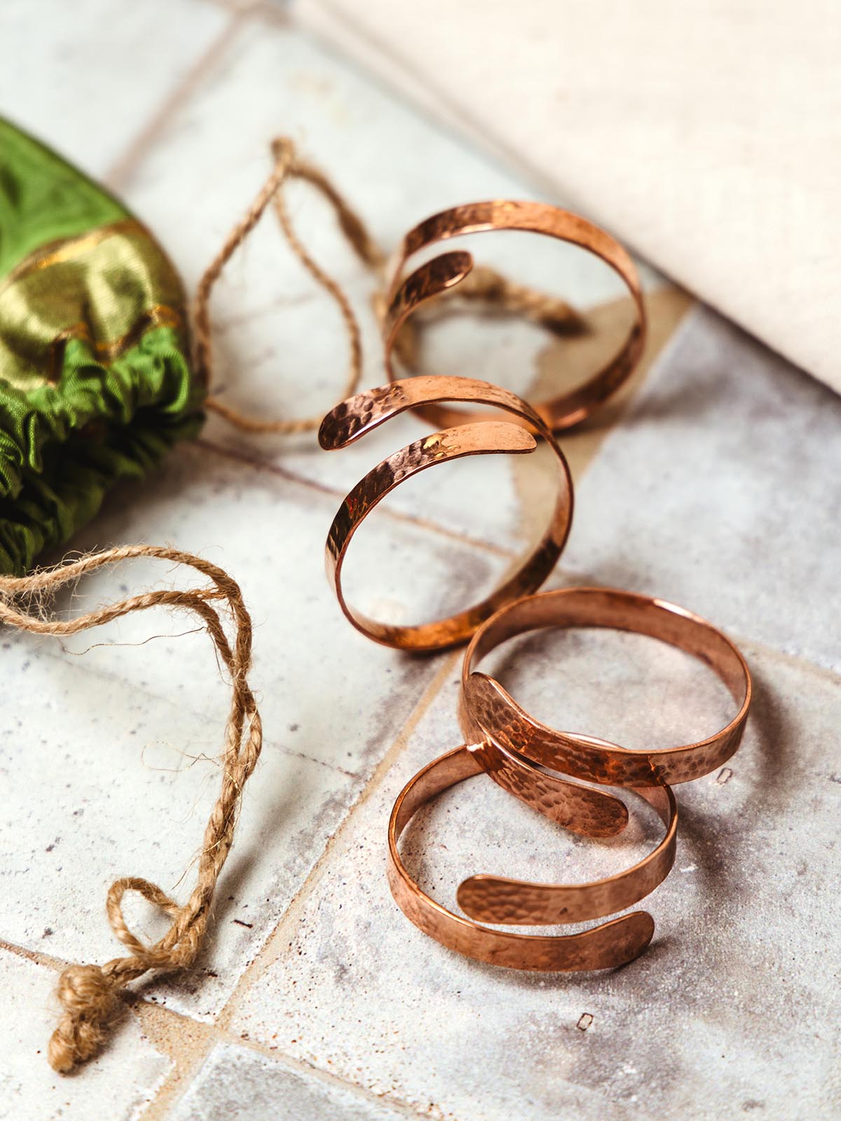 Close-up of handcrafted hammered copper napkin rings, featuring a unique spiral design, part of Joffa.com's sustainable and artisanal home decor collection.