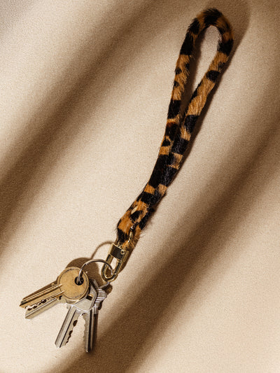 Trendy leopard print wristlet keychain with attached keys, featuring a durable gold clasp. Perfect for adding a touch of style to daily essentials.