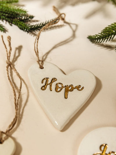 Close up of Gold Leaf Pottery Ornaments on cream background with Christmas greenery.