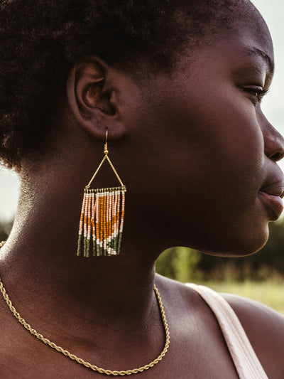 African female model wearing fringe earrings with nature in the background. 