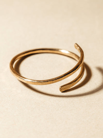 Gold hammered wrap ring on cream background.