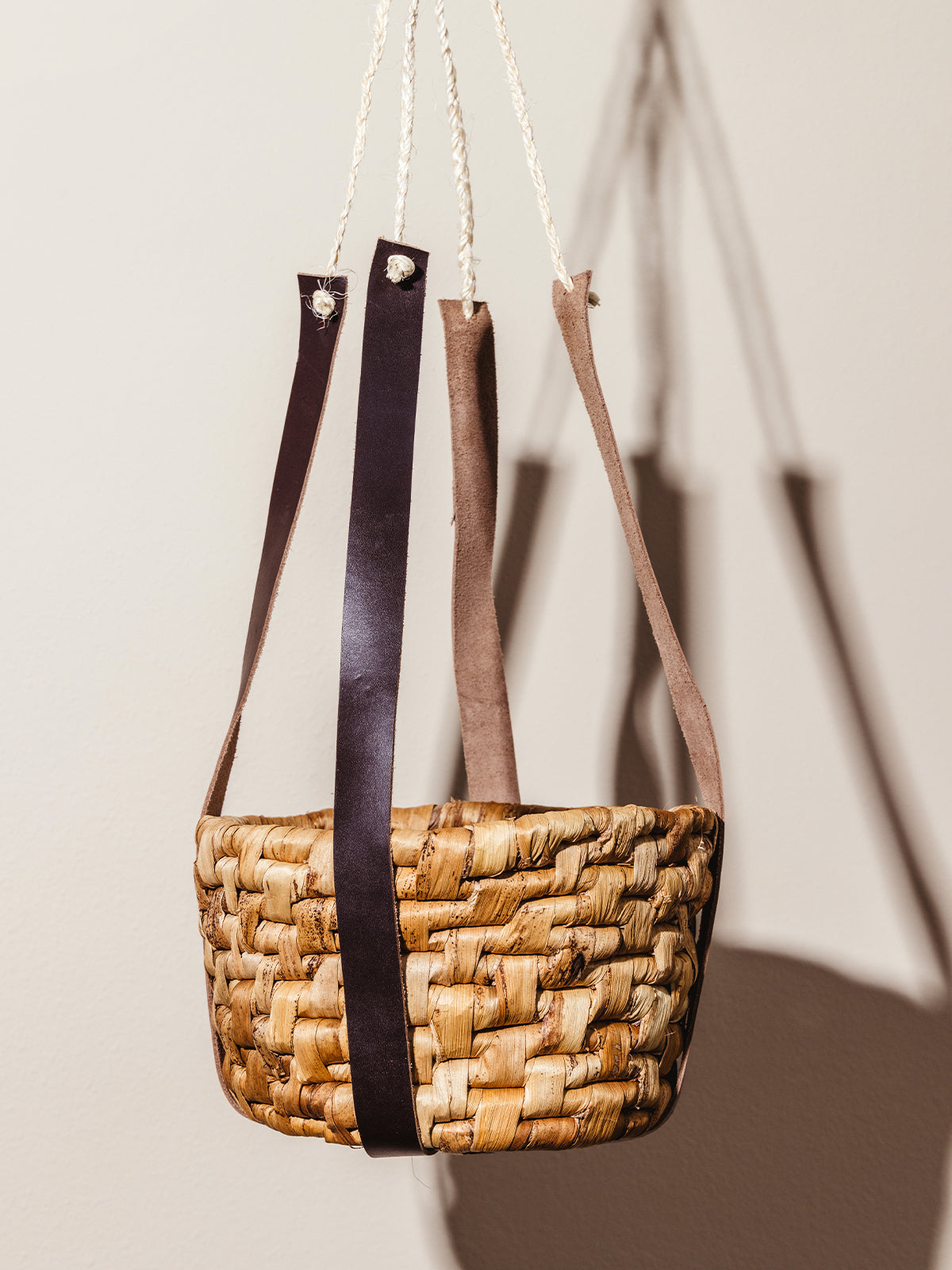 Empty leather banana leaf hanging basket on cream background.