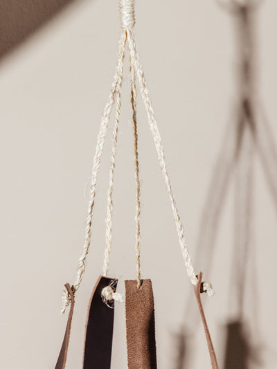 Close up of hanging material and leather straps over cream background. 