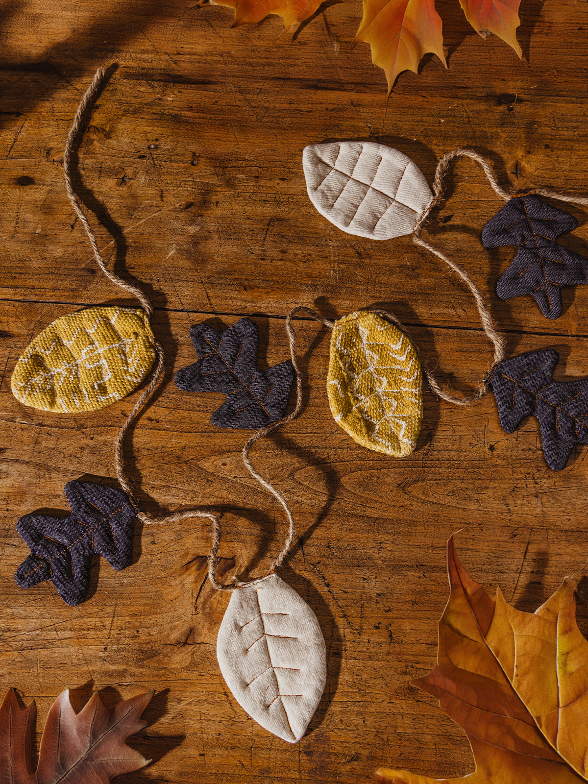 Fall leaf garland on wooden table with fall leaves.