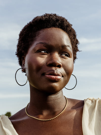 Portrait of African female wearing Cafe Hoops with sky background.