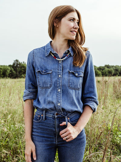 Female model with red hair wearing all denim wearing beaded Milot Necklace in outdoor setting. 