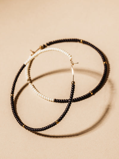 Black and white beaded cafe hoops on cream background.