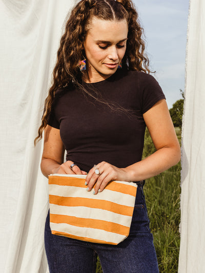 Female e holding striped waterproof pouch in outdoor setting.