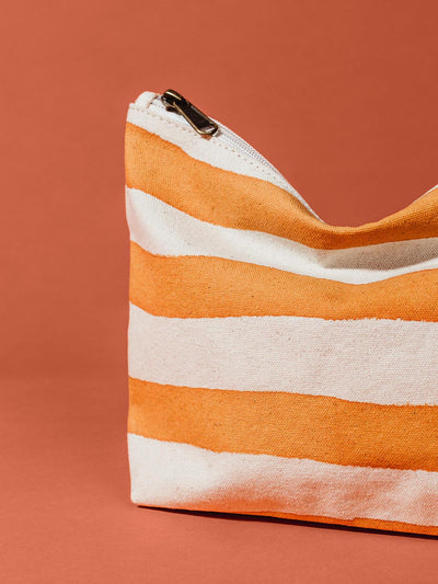 Close up of orange and white striped waterproof pouch on rustic orange background.