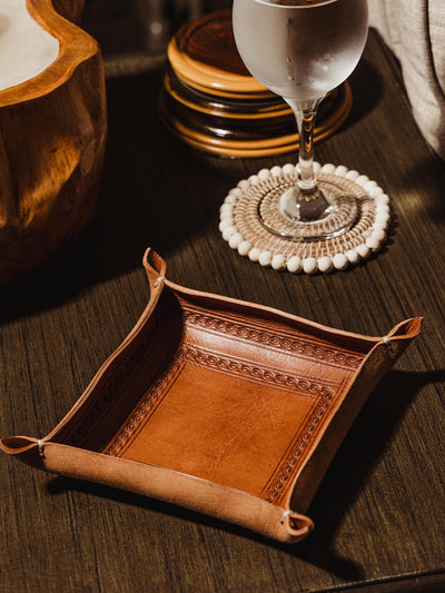 Jubilee leather stamped valet tray on living room table with water glass and coaster. 