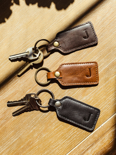 Leather keychains with keys on wood table.