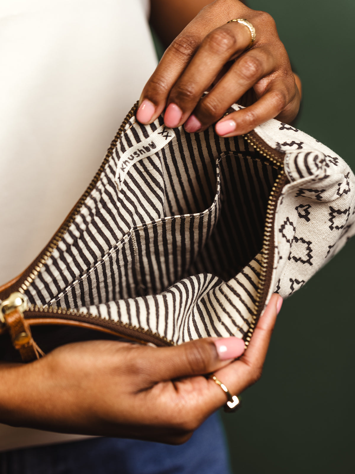 Close-up of the interior of a handcrafted clutch bag, showing striped fabric lining and an inner pocket with a 'Khushbu' label. Ideal for organizing essentials with a touch of sophistication.