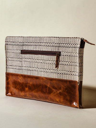 Back view of a modern laptop sleeve with a stylish geometric pattern and brown leather base, showcasing a practical zipper pocket for organization. Ethically made and durable for everyday use.