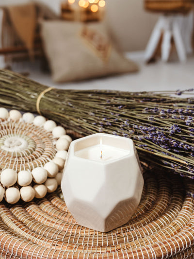 Small ceramic prism candle burning in styled tray in living room setting. 