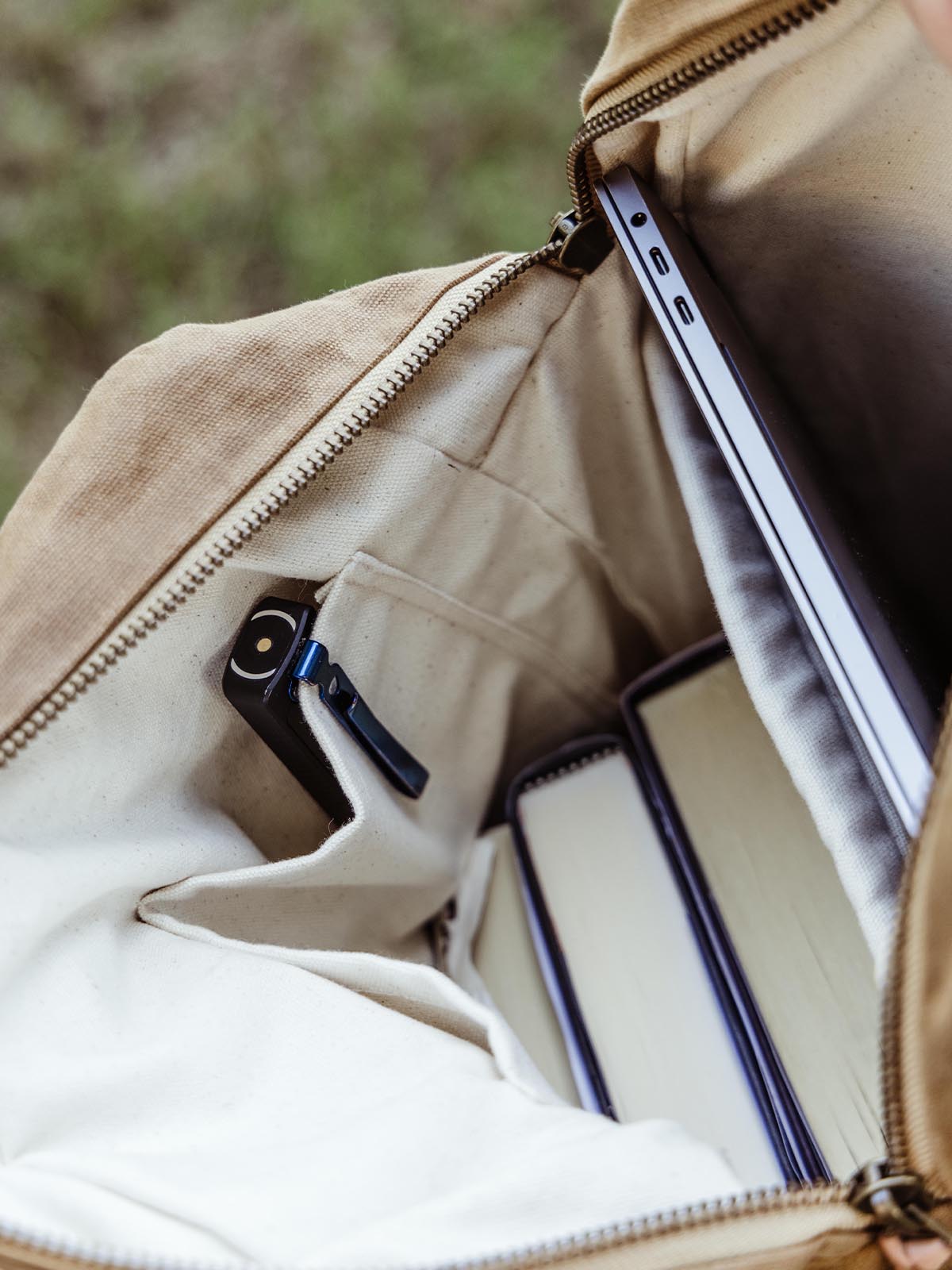 Interior view of a canvas backpack, showing a laptop and books stored securely. Versatile backpack with organized compartments for travel or commuting.