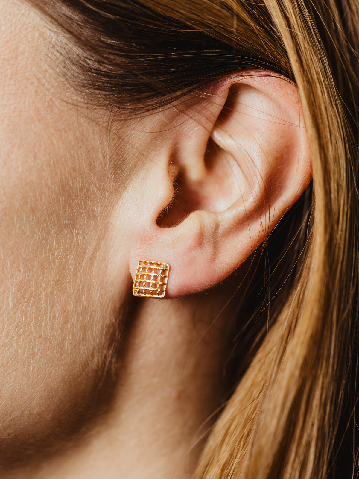 Gold lattice stud earrings styled with fresh lime slices, emphasizing their artisanal craftsmanship and modern geometric design.