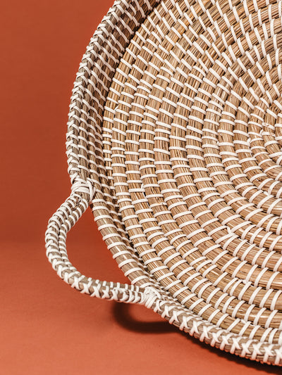 Closeup of woven Kaisa Tray on rust orange studio background.