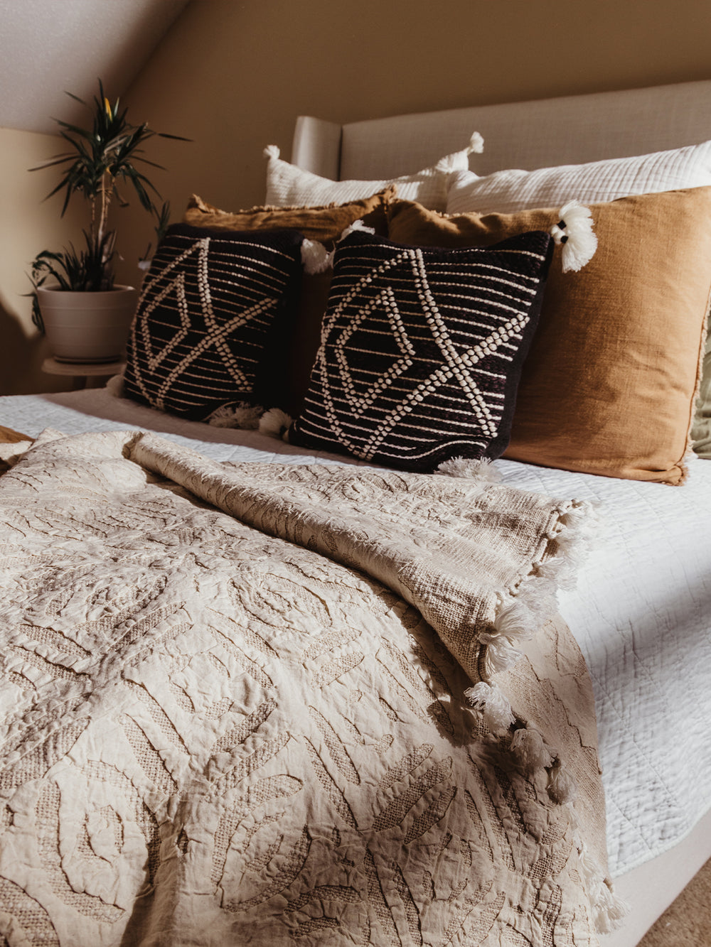 Cream Cutwork throw blanket on cream styled bed in bedroom setting. 