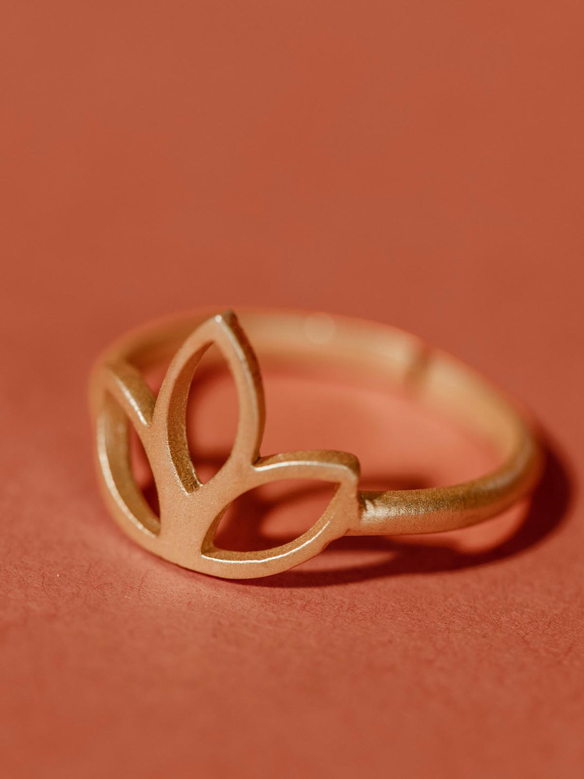 Golden lotus flower ring on tuscan red background. 