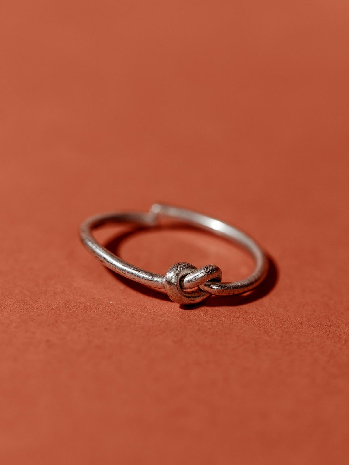 Silver knotted in faith ring on tuscan red background.