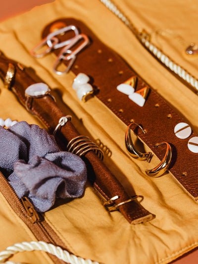 Close inside view of velvet jewelry organizer featuring pockets for bracelets and necklaces, as well has a leather earring storage and ring holder.