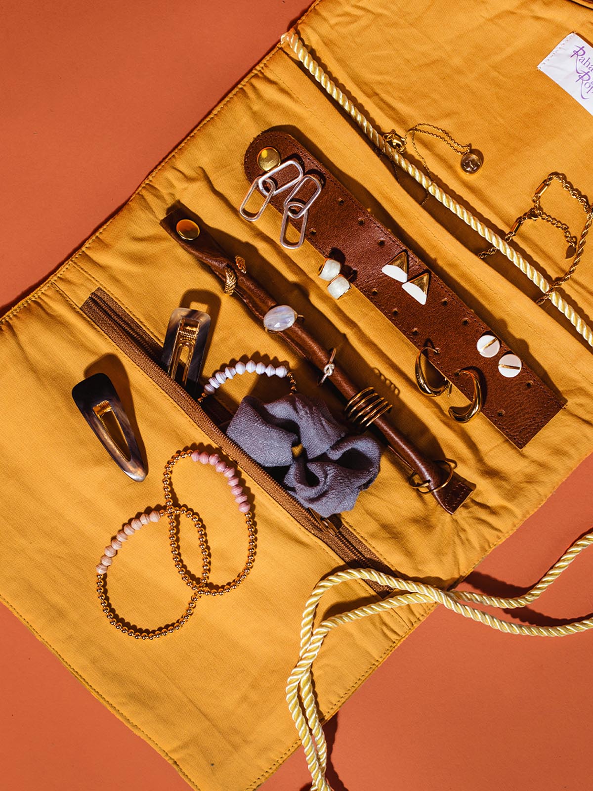 Inside view of velvet jewelry organizer featuring pockets for bracelets and necklaces, as well has a leather earring storage and ring holder.