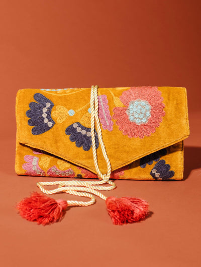 Velvet jewelry organizer with floral patter and tassel ties undone on tuscan red background.