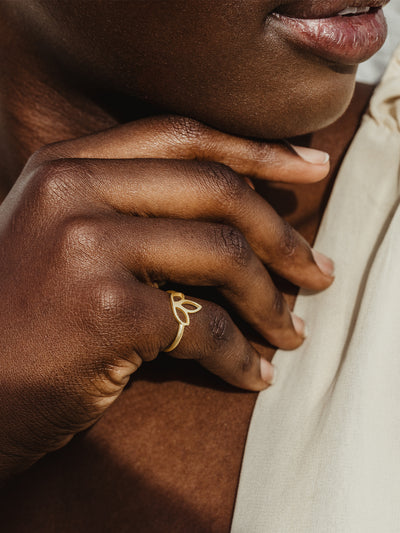 African female model close up of hand wearing gold lotus ring.