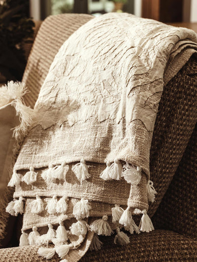 Cream cutwork throw dropped over chair in living room space.