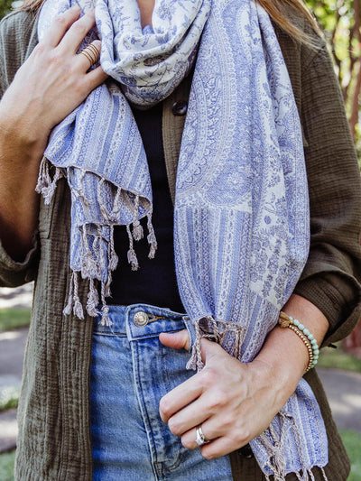 Close-up of a blue and white paisley shawl wrapped around a woman's neck, highlighting the intricate pattern and lightweight fabric, available at Joffa.com.