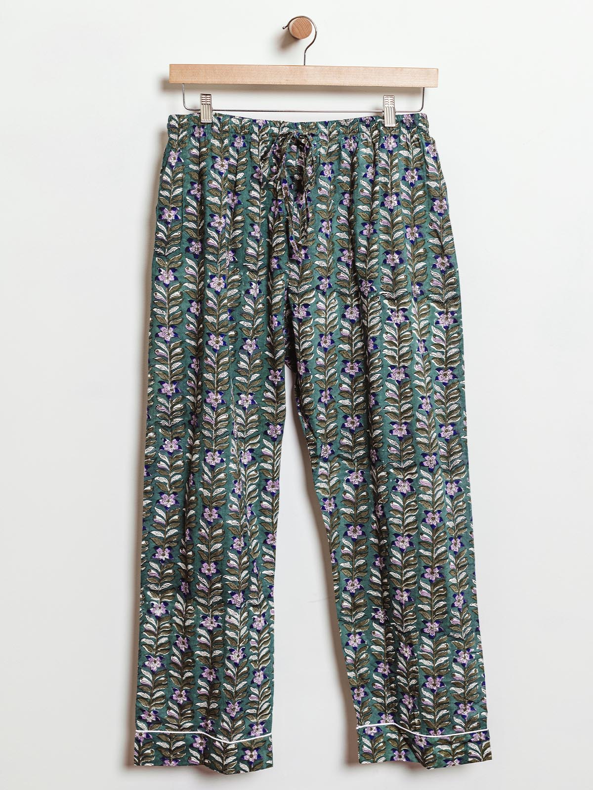 Ethically made lounge pants in green with a purple floral and vine pattern, featuring an elastic waistband and drawstring for an adjustable fit. Handcrafted from soft fabric, these sustainable pants offer comfort and style for lounging or casual wear.