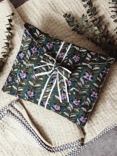 Beautifully wrapped robe featuring a blue/green floral design, tied with a white ribbon. Displayed on a soft cream and blue quilt with eucalyptus sprigs for a touch of nature. Ethically made and perfect for gift giving.