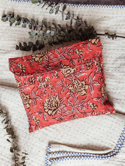 Handcrafted red floral pouch with yellow flower designs, resting on a cream quilt with blue stitching and decorated with eucalyptus sprigs. This ethically made pouch is perfect for storing small items and makes a thoughtful, sustainable gift.