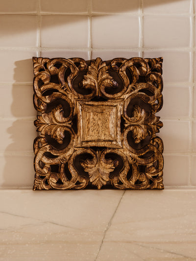 Wood ornate hand carved trivet on kitchen counter ledge as decor.