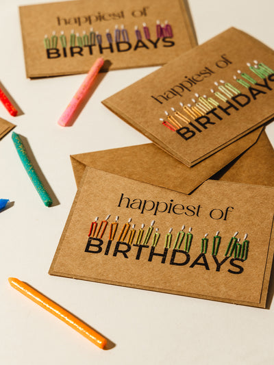 Flat lay of embroidered happy birthday cards featuring multicolored stitched candles, paired with glittering birthday candles on a neutral background. Ideal for celebrating special moments with a personal and creative style.