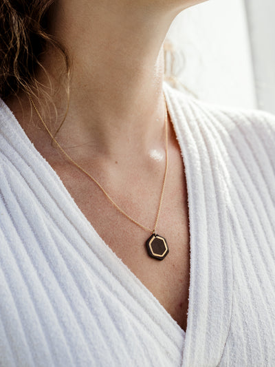 Close up image of white female model in white sweater dress on white background wearing robin hexagon necklace. 